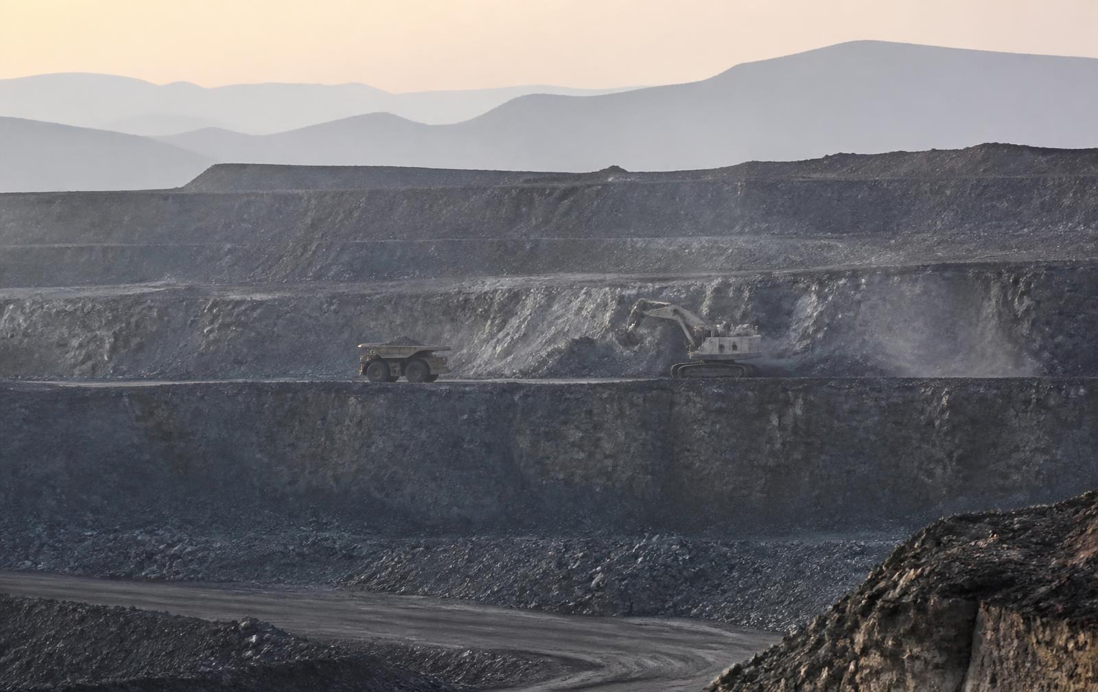 Frente de lavra em mina a céu aberto com caminhão fora de estrada e escavadeira em operação